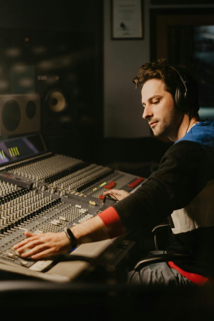 pexels photo 4988134 4988134 A focused sound engineer operates a mixing panel in a professional recording studio.
